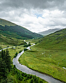 Luftaufnahme eines sich windenden Flusses und einer Straße durch üppig grüne Täler und majestätische Berge, Kyle, Vereinigtes Königreich.