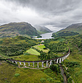 Aerial view of the iconic Glenfinnan Viaduct amidst majestic mountains and a serene valley, Glenfinnan, United Kingdom.
