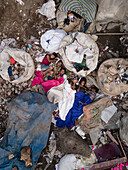 Dhaka, Bangladesh - 27 March 2023: Aerial view of children sleeping on makeshift beds amidst plastic waste and garbage in a crowded urban environment, Dhaka, Bangladesh.