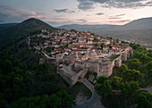 Aerial view of berat castle and old town surrounded by mountains and greenery at sunset, berat, albania.