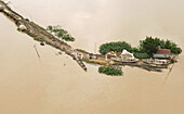 Aerial view of a flooded village with wooden homes and boats amidst waterlogged landscape, Uttar Badaghat, Tahirpur, Bangladesh.