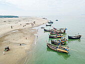 Aerial view of fishing boats at the fishery ghat by the Bay of Bengal with a sandy shore and clear sky, Cox Bazar, Bangladesh.