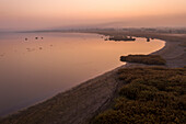 Aerial view of serene sunrise over a tranquil lake surrounded by picturesque fields, Vassiloudi, Greece.
