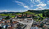 Aerial view of town square with church and abbey surrounded by hills and fields, Einsiedeln, Switzerland.