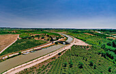 Luftaufnahme der üppigen Weinberge und des sich schlängelnden Kanals mit Boot, Argeliers, Narbonne, Frankreich.