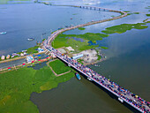 Aerial view of Sheikh Hasina Bridge over a scenic river with boats and vehicles, Dakshin Shuhilpur, Brahmanbaria, Bangladesh.