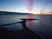 Aerial view of the sunset reflecting off the water over the golf course of Golfklúbbur - Seltjarnarnes, Reykjavik, Iceland.