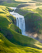 Aerial drone view of Skógafoss waterfall during sunrise in summer time, Southern Iceland.