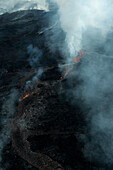Aerial view of the active Fagradalsfjall volcano with flowing lava and smoky clouds, Grindavik, Iceland.