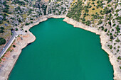Luftaufnahme des Stausees Torrent de Gorg Blau mit grünem Wasser, Felsen und Vegetation in der Umgebung auf Escorca, Balearen, Spanien.