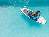 Aerial view of a woman on a SUP or stand up paddle in swimming pool.