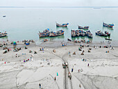 Aerial view of fishing boats at the fishery ghat by the Bay of Bengal with people engaging in trade, Cox Bazar, Bangladesh.