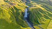 Aerial drone view of Skógafoss waterfall during sunrise in summer time, Southern Iceland.