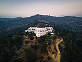 Aerial view of griffith observatory at sunset surrounded by mountains and trees, los angeles, united states.