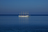 Aerial view of a golden horizon ship sailing on a calm sea with a beautiful perspective, Sarande, Albania.