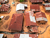 Aerial view of rustic village with red rooftops and dirt roads, Irewole, Nigeria.