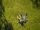 Aerial view of family laying down on grass at public playground, Zagreb.