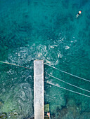 Aerial view of people swimming in algae accumulation in the turquoise sea, Pula, Croatia.