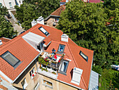 Aerial view of family having breakfast on rooftop balcony in morning sun in Spring.