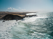 Luftaufnahme der Wellen, die an die Felsen von Punta Guadalupe auf Fuerteventura, Kanarische Insel, schlagen.