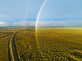 Aerial view of full rainbow over green landscape with ring road, south Iceland.