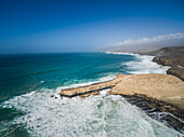 Luftaufnahme der Wellen, die an die Felsen von Punta Guadalupe auf Fuerteventura, Kanarische Insel, schlagen.