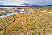 Aerial view of Svarta river and low vegetation in front of Kjalfell mountain with rain showers in the Kjolur area in the highlands of Iceland