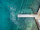 Aerial view of people swimming in algae accumulation in clear turquoise sea, Pula, Croatia.