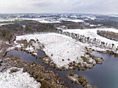 Aerial view of lake in nature area Witte Veen covered with snow, Twente, Overijssel, Netherlands.