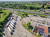 Luftaufnahme einer belebten Tankstelle und einer Autobahn mit geparkten Lastwagen, Cessalto, Italien.