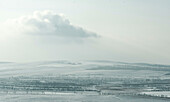 Aerial view of vast snowy steppe under a serene sky with clouds, Khakassia Republic, Russia.
