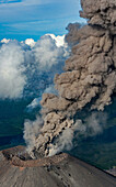 Aerial view of Karymsky volcano with smoke and ash amidst dramatic clouds, Kamchatka peninsula, Russia.