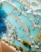 Aerial view of turquoise ocean with sunbathers at Saturnia spa, Cascate del Mulino, Hot Spring, Manciano, Italy.