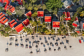 Luftaufnahme eines Hotels am Strand mit roten Dächern und schattenwerfenden Sonnenschirmen, Flic en Flac, Mauritius, Afrika