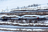 Aerial view of snowy remote road with trucks in a beautiful winter landscape, Karelia Republic, Russia.