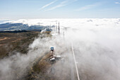Aerial view of foggy landscape with radar antenna and clouds over rugged mountains, Santa Barbara, Azores, Portugal.
