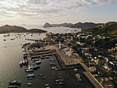 Der Hafen von Labuan Bajo mit einem im Meer segelnden Boot und dem Stadtbild, Touristenziel in Indonesien.