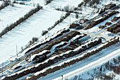 Aerial view of snowy winter landscape with lumber woodpile and forest, Karelia republic, Russia.