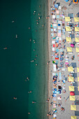 Aerial view of a crowded beach with colorful umbrellas and sunbathers under sunny skies, Koktebel, Russia.