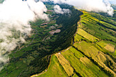 Luftaufnahme eines Kraterrandes mit Wolken und Feldern, Sao Miguel, Azoren, Portugal.