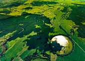 Luftaufnahme eines wunderschönen Sees, umgeben von üppigem Grün und einem gewundenen Fluss, Gebiet Omsk, Russland.