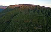 Aerial view of Takamaka mountains at sunrise with mist over lush fern trees, Saint Benoit, Reunion.