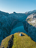 Aerial View of hiker with tent admiring view od Swiss Mountain Lake in Glarus, Switzerland.