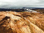 Aerial view of a volcanic hot spring with sulphuric smoke and a lake in background, Namafjall Hverir viewpoint, Northeastern Region, Iceland.