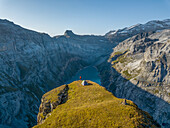 Aerial View of hiker with tent admiring view od Swiss Mountain Lake in Glarus, Switzerland.