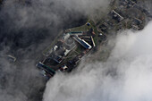 Aerial view of a mystical fortress surrounded by clouds and a tranquil village, Onega Bay, Russia.