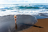 Luftaufnahme einer Frau im Bikini am Strand, die ihre Sonnenbrille hält, Sao Miguel, Azoren, Portugal.