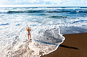 Luftaufnahme einer Frau im Bikini am Strand, die ihre Sonnenbrille hält, Sao Miguel, Azoren, Portugal.