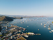 Der Hafen von Labuan Bajo mit einem im Meer segelnden Boot und dem Stadtbild, Touristenziel in Indonesien.