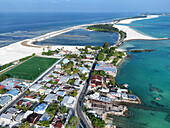 Aerial view of artificial reclamation with palm trees and houses along the turquoise ocean, Maradhoo, Maldives.